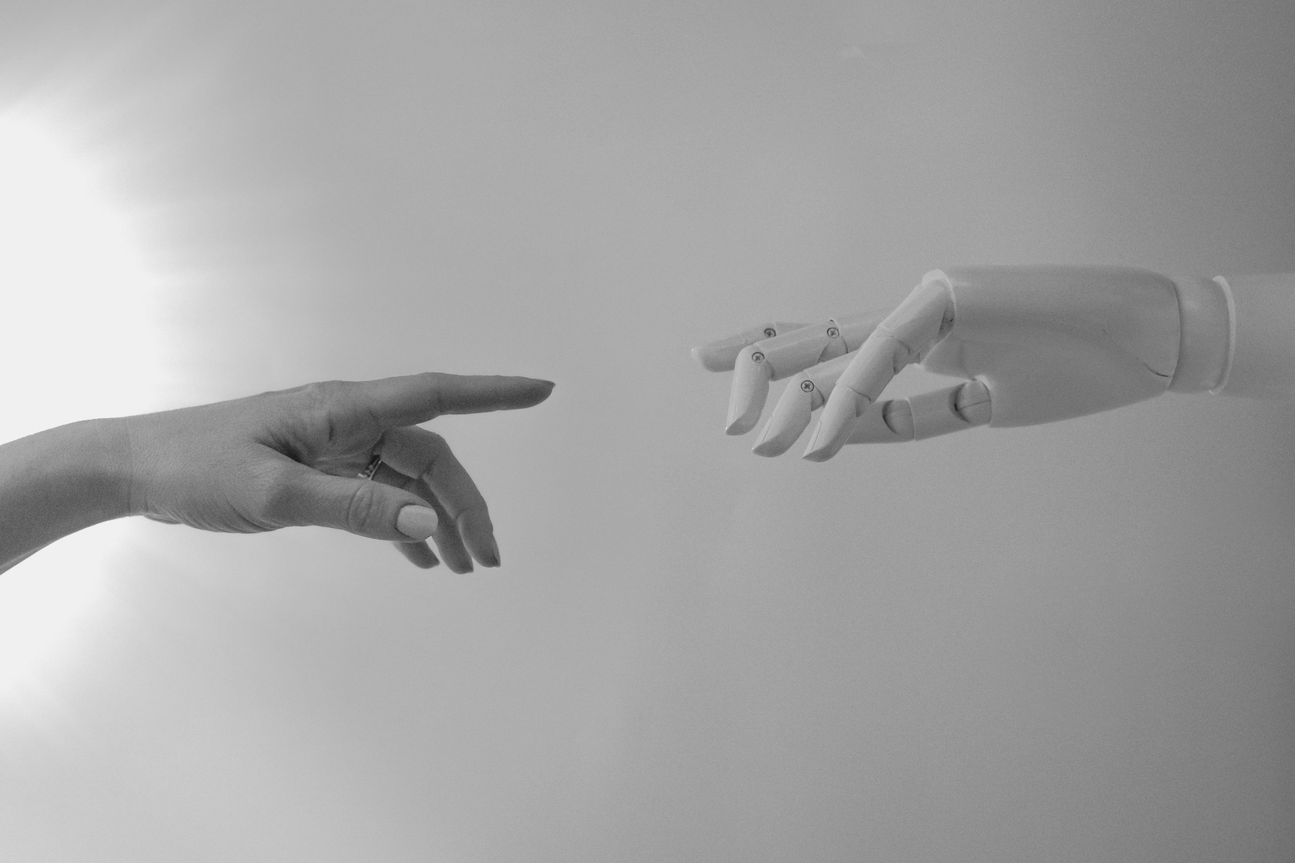 A human and a robot hand replicating the painting "The creation of adam" on white background